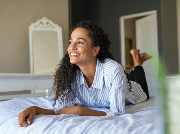 Happy young mixed race woman relaxing on bed