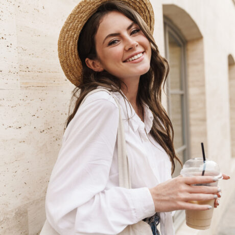 Portrait of beautiful joyful woman smiling and drinking milkshake