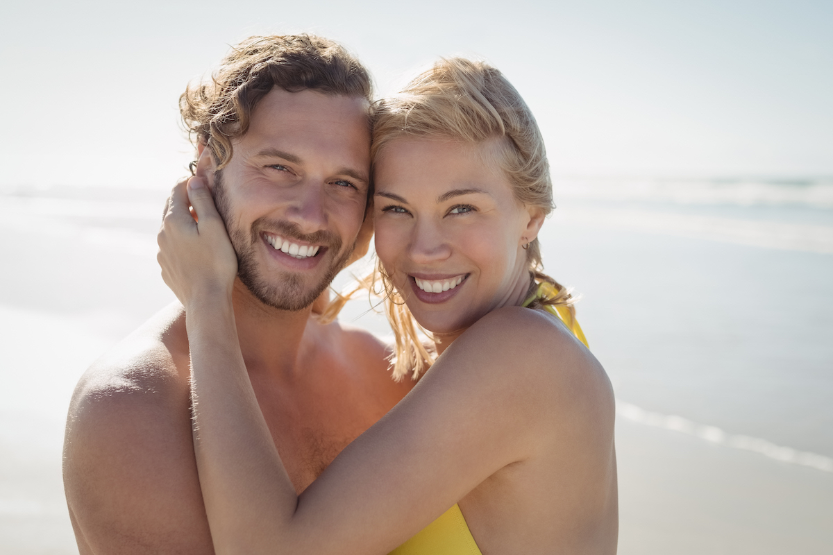 Portrait of smiling couple embracing at beach